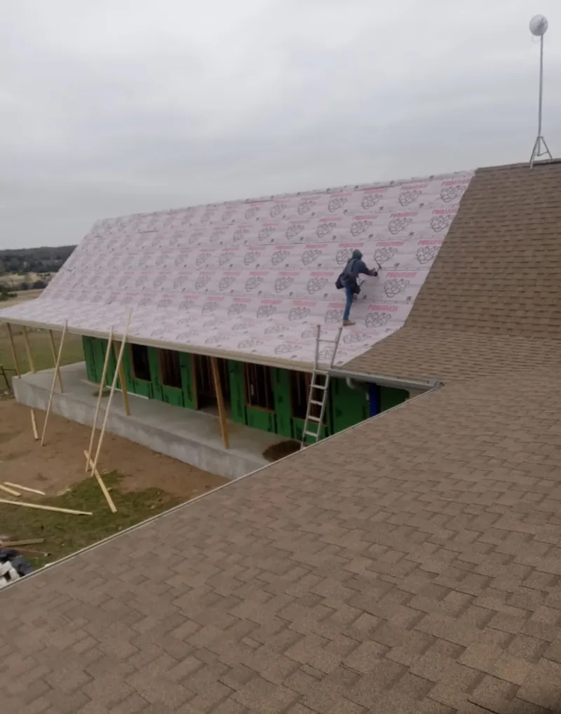 Worker preparing underlayment for a metal roof installation in Salmon Creek